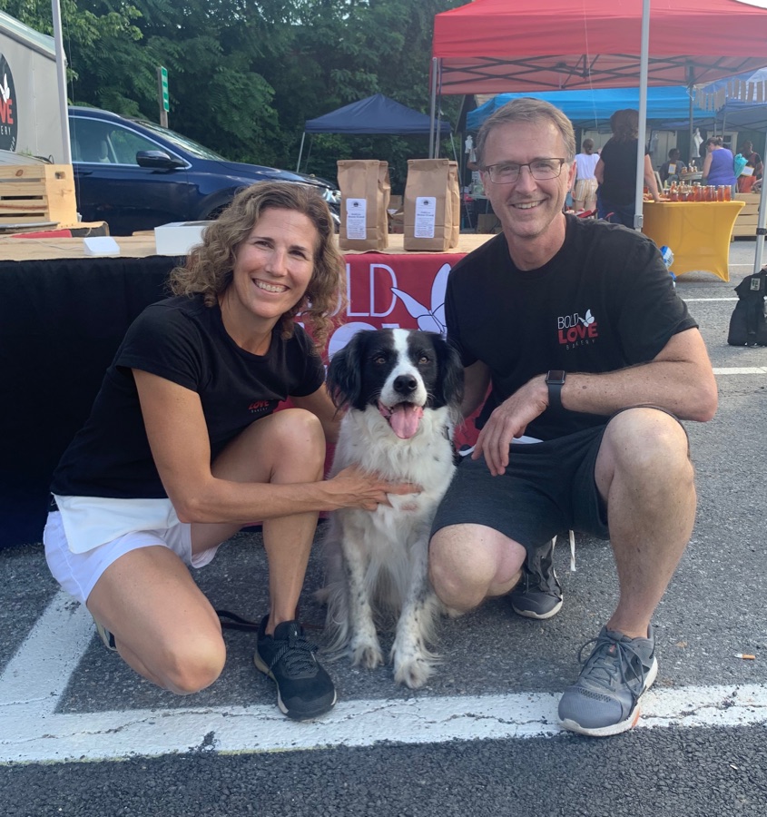 Kim and George smiling with their dog at the bakery's market stand